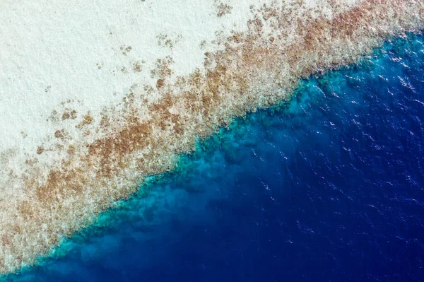 Saf mavi okyanus suyunun yüksek açılı insansız hava aracı görüntüsü kıyı şeridi kayalık kaya kayalıkları mercan resifleri yaz tatilinde turizm turizmini yıkıyor. — Stok fotoğraf