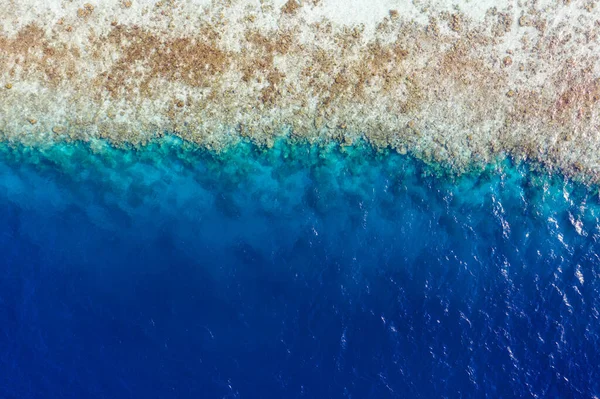 Yüksek açılı, temiz, mavi okyanus suyunun, deniz kıyısındaki mercan resiflerini yıkamasının insansız hava aracı görüntüsü. Lüks turist turları. Yaz mevsiminde sıcak satış. Sri Lanka 'ya erken rezervasyon. — Stok fotoğraf
