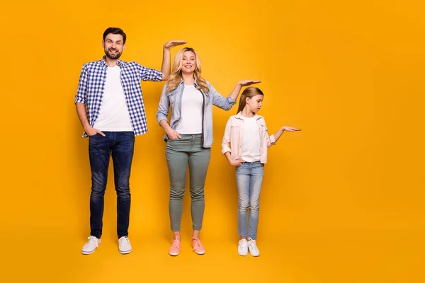 Foto em tamanho completo de três membros família mãe pai filha não acredito rápido crescendo medir comprimento altura bom humor desgaste casual roupa isolado cor amarela fundo — Fotografia de Stock