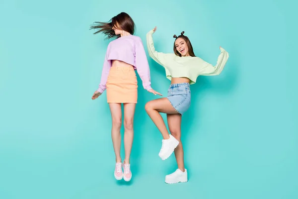 Full length body size of two nice attractive slim fit girlish cheerful cheery girls having fun jumping dancing fooling isolated over bright vivid shine vibrant blue turquoise color background — стоковое фото