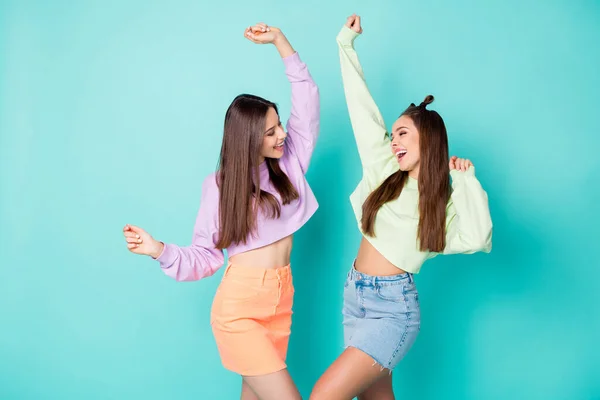 Foto van twee vrolijke dame vriendinnen vieren studentenfeest begin koele jeugd look kleding bijgesneden truien naakte buik korte rokken geïsoleerde pastel teal kleur achtergrond — Stockfoto