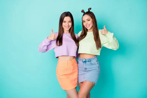 Photo de deux belles amies fraîches vêtements de jeunesse lever les doigts du pouce conseiller belle offre porter vert recadré chandails violets mini jupes isolé fond de couleur sarcelle pastel — Photo