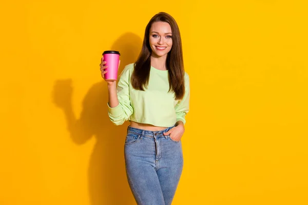 Photo of attractive lady good mood street look drink takeout coffee beverage pink cup wear green cropped sweatshirt jeans isolated vivid bright yellow color background — Stock Photo, Image