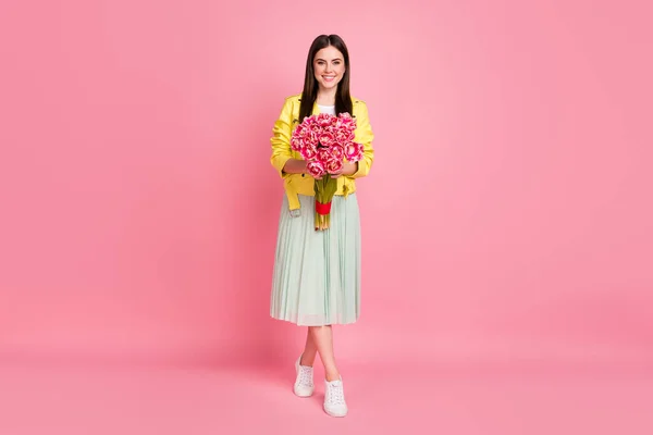 Plná délka fotografie pěkné veselá dáma držet velké čerstvé tulipány parta vděčný kompliment oblečení trend žlutá kůže bunda zelená sukně obuv izolované pastel růžová barva pozadí — Stock fotografie