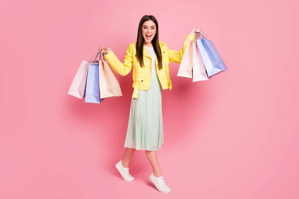 Full längd foto av söt dam hålla många shopping förpackningar köpa nya kollektion kläder bära trend gult läder jacka lång kjol skor isolerad pastell rosa färg bakgrund — Stockfoto