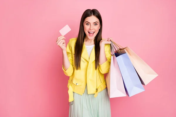 Photo of pretty lady choosing clothes hold many shopping packs plastic bonus card buying new collection wear trend yellow leather jacket skirt isolated pastel pink color background — Stock Photo, Image