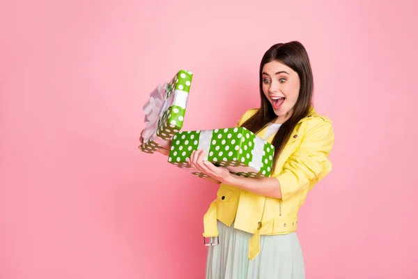 Foto de perfil de la señora encantadora divertida cogida de la mano grande caja de regalo verde abriendo la boca abierta llena de alegría desgaste tendencia chaqueta de cuero amarillo falda aislado pastel color rosa fondo —  Fotos de Stock