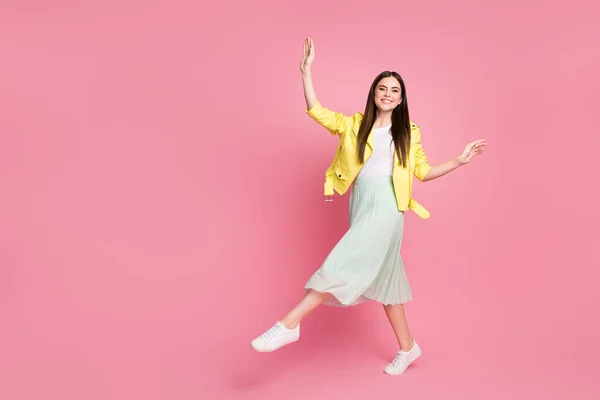 Full body profile photo of funky lady raise arms walking down street good mood wear trend yellow leather jacket green long skirt sneakers isolated pastel pink color background — Stock fotografie