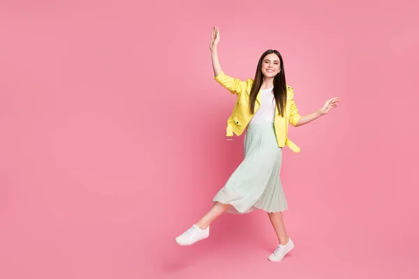 Foto de perfil de corpo inteiro de senhora funky levantar braços andando rua bom humor desgaste tendência amarelo jaqueta de couro verde saia longa tênis isolado pastel cor rosa fundo — Fotografia de Stock