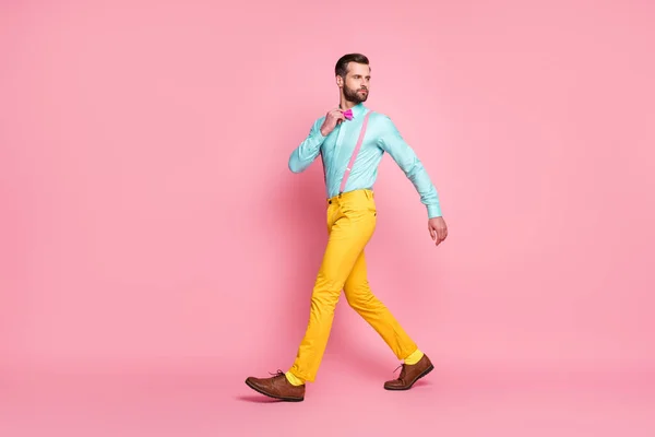 Volledige lengte profiel foto van knappe man trend kleding lopen kantoor corporate vergadering dragen shirt bretels strik geel broek schoenen geïsoleerde pastel roze kleur achtergrond — Stockfoto