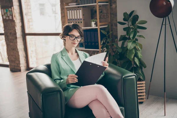 Zaměřeno dívka vedoucí marketer dívka sedět kožené opěradlo židle číst kontrolní seznam klip palubě analyzovat start-up zpráva nosit zelené sako růžové kalhoty brýle v moderní kanceláři — Stock fotografie