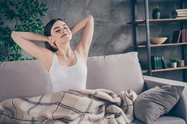 Портрет мирной спокойной девушки проснуться после здорового сна взгляд наслаждаться растянуть руки сидеть диван ноги покрывают клетчатое одеяло в доме в помещении — стоковое фото