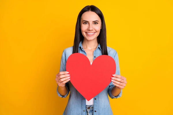 Close-up portrait of her she nice attractive lovely pretty cheerful cheery girl holding in hand paper heart form shape affection isolated over bright vivid shine vibrant yellow color background — Stock Photo, Image