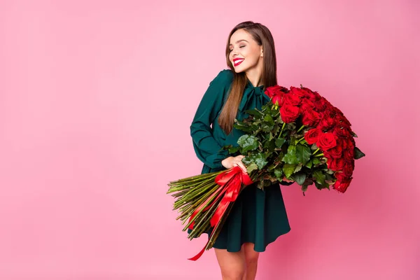 魅力的なシックな女性の写真は大きな赤い長いバラの花束を保持します喜びボーイフレンドの夫の誕生日サプライズは緑のミニドレス孤立パステルピンク色の背景を身に着けています — ストック写真