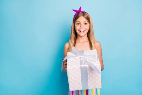 Hayretler içinde kalmış neşeli kız çocuğu portresi büyük noktalı hediye paketi taşıyor. Mavi arka planda izole edilmiş moda kıyafetler giyiyor. — Stok fotoğraf