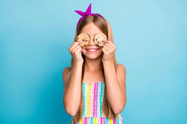 Retrato de menina alegre positiva segurar biscoitos de chocolate fechar os olhos rosto desfrutar de lanche desgaste brilho saia elegante moda isolado sobre fundo de cor azul — Fotografia de Stock