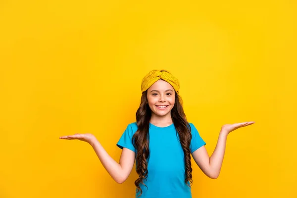 Фото красивої моделі маленької леді тримає відкриті руки, демонструючи поради двох новинок продажу продуктів вибору одягу з повсякденною синьою футболкою головний убір ізольований жовтий кольоровий фон — стокове фото