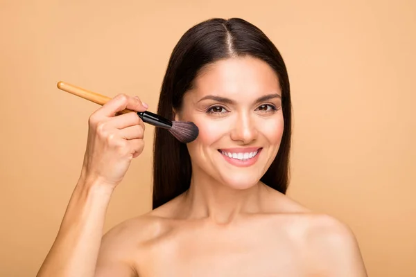 Close-up portret van haar ze mooi uitziende aantrekkelijke mooie vrolijke vrolijke vrouw met behulp van rouge base gezichtsherkenning bronzer geïsoleerd over beige pastel kleur achtergrond — Stockfoto