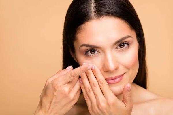 Closeup foto de maduro nu senhora modelo beleza natural sem maquiagem segurando dedo novo contato lente colocando-o no olho isolado bege pastel cor fundo — Fotografia de Stock