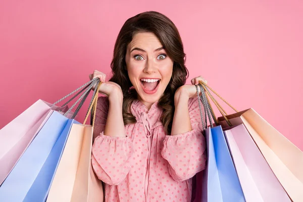 Close up retrato de espantado deslumbrante linda senhora segurando muitos sacos de compras gritando sim isolado sobre pastel rosa fundo — Fotografia de Stock