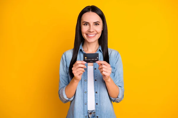 Retrato dela ela agradável atraente linda menina alegre bonita empresária segurando em mãos cartão de banco isolado no brilho vívido brilhante cor amarela vibrante fundo — Fotografia de Stock