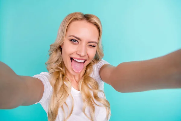 De cerca la foto de la chica alegre positiva disfrutar de vacaciones de fin de semana de verano hacer selfie mostrar la lengua hacia fuera guiño parpadear el estilo de desgaste ropa de moda con estilo aislado sobre fondo de color verde azulado — Foto de Stock