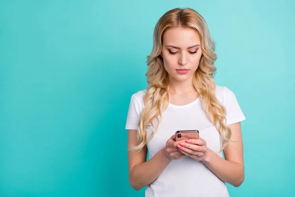 Портрет зосередженої дівчини використовує смартфон, читає інформацію в соціальних мережах, добре виглядає одяг ізольований на бірюзовому кольоровому фоні — стокове фото