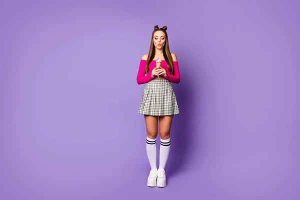 Полноразмерная фотография смешной голодной дамы, держащей в руках мороженое, одетой в розовую обрезную верхнюю юбку с длинным коленом и туфли на фоне фиолетового цвета — стоковое фото