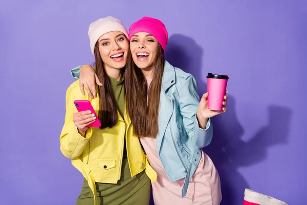 Porträtt av trevliga attraktiva ganska glada flickor med cell dricka latte har kul bästa vänner vänskap skugga isolerad på ljusa levande glans levande violett lila lila färg bakgrund — Stockfoto