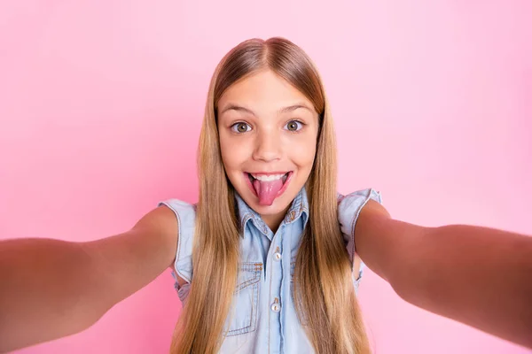 Close up photo of cute playful kid girl blogger grimace face show tongue out make selfie wear denim clothes isolated over pastel color background — Stock Photo, Image