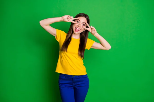 Retrato de despreocupado adolescente menina enganando desfrutar de descanso relaxar fazer v-sinal rosto mostrar língua para fora desgaste bom olhar calças isoladas sobre fundo de cor brilhante — Fotografia de Stock