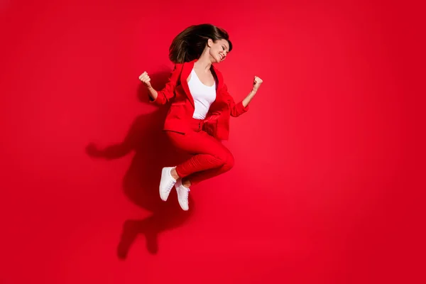 Full body photo of attractive lady successful worker having fun jumping high up good mood celebrating startup success wear blazer suit pants footwear isolated bright red color background — Stock Photo, Image