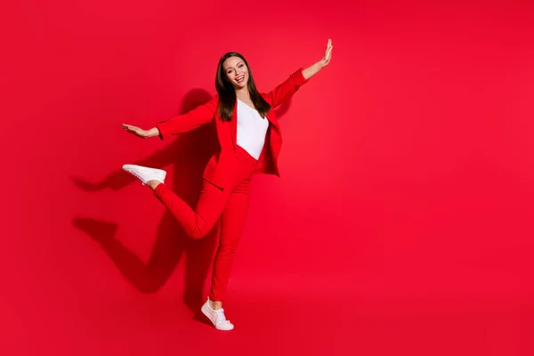 Volledige lengte profiel foto van aantrekkelijke grappige zakelijke dame werknemer lopen naar huis straat met plezier verspreid armen doen alsof vlucht dragen blazer pak broek witte schoenen geïsoleerde rode kleur achtergrond — Stockfoto