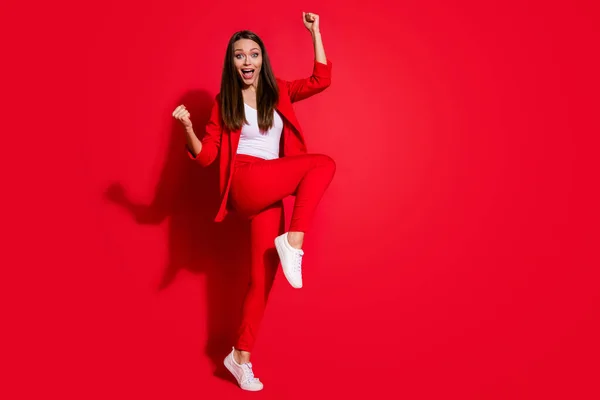 Ganzkörperfoto von crazy business lady manager heben bein fäuste nach oben ekstatische unglaubliche leistung cool tragen büro blazer hose anzug schuhe isoliert rote farbe hintergrund — Stockfoto