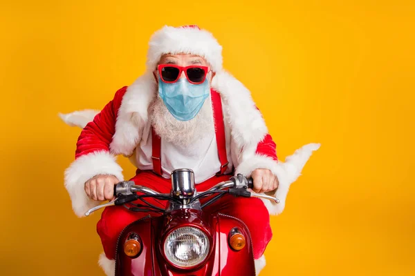 Portret jego miły funky hipster siwe włosy starsze Santa noszenie maski ochronnej gazy jazdy motorower szybko dostarczając prezenty pobyt w domu wyprzedaż odizolowany nad jaskrawo żywy żółty kolor tła — Zdjęcie stockowe