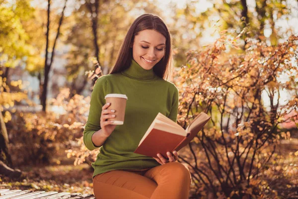 Photo of lovely charming lady come autumn park relax drink kávé olvass fikció regény fantáziál magát hercegnő más lelki világ mosolygós viselni zöld garbó narancs nadrág szabadban — Stock Fotó
