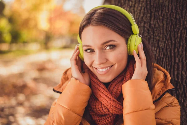 Närbild headshot foto av ganska charmig dam strålande leende sittplats bland gulnade blad höst park lyssna kylande musik bära hörlurar halsduk orange windbreaker utanför — Stockfoto