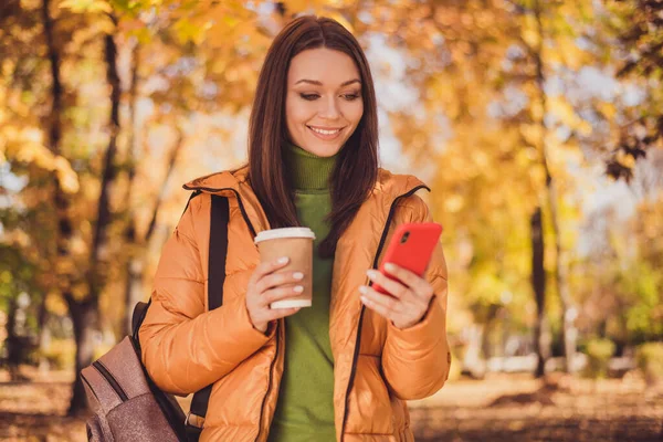 원문 기사보기 매력적 인 여성이 웃으며 전화를 하는 사진 - 인터넷 가을 공원에서 커피를 마시며 인사하는 모습 - 배낭 안에 녹색 터틀넥 스웨터를 입고 밖에 나가 있는 모습 — 스톡 사진