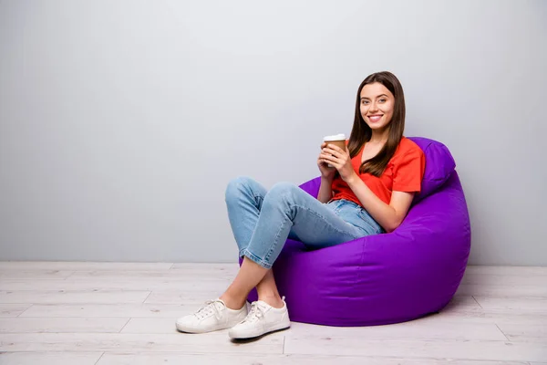 Retrato dela ela agradável atraente linda alegre menina alegre freelancer sentado no saco gostando de beber café expresso doce quente espera emprego entrevista no café luz cinza parede de cor pastel dentro de casa — Fotografia de Stock