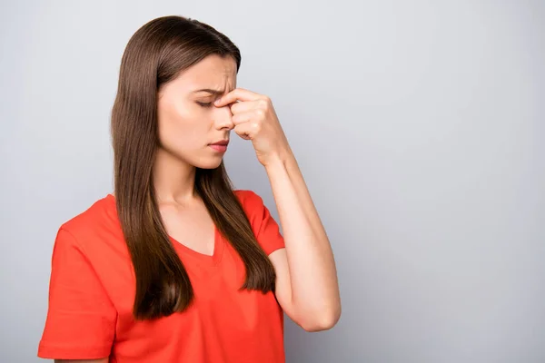 Close-up profiel zijaanzicht portret van haar ze mooi aantrekkelijk verdrietig recht-harig meisje dragen oranje t-shirt aanraken neus met hoofdpijn geïsoleerd op licht grijs pastel kleur achtergrond — Stockfoto