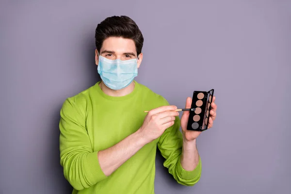 Retrato dele ele atraente cara make-up artista vestindo máscara de gaze de segurança segurando na mão olho sombra paleta mers cov influenza prevenção desinfecção medidas de higiene isolado cor cinza fundo — Fotografia de Stock