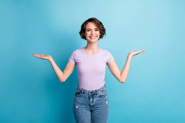 Foto von positiven fröhlichen Mädchen halten Hand vorhanden Anzeigen Promo Objekt Produktangebot tragen gutes Aussehen Outfit isoliert über blauen Farbhintergrund — Stockfoto