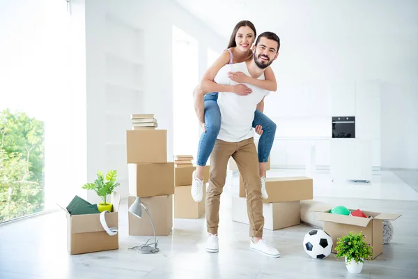 Full length body size view of his he her she nice attractive cheerful cheery positive married spouses guy piggy-backing girl having fun at light white interior house indoors — Stock Photo, Image