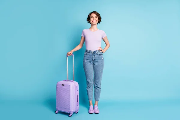 Портрет позитивного веселого путешественника держать чемодан готовый к отъезду назначения носить хороший вид одежды gumshoes изолированы на синем фоне цвета — стоковое фото