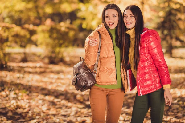 Photo of two girls have autumn forest walk see animals point index finger wear bright outerwear hold bag backpack — Stock Photo, Image