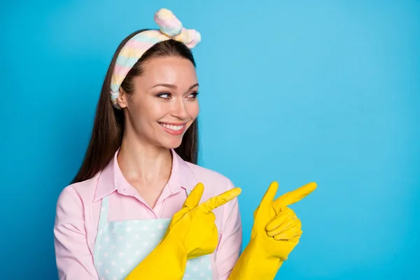 Nahaufnahme Foto von attraktiven Dame Hausmädchen Latex-Handschuhe Frühjahrsputz Richten Finger Seite leeren Raum zeigt Angebot tragen Stirnband gepunktet Schürze Hemd isoliert blaue Farbe Hintergrund — Stockfoto