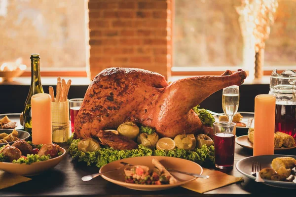 Foto de primer plano de gran asado asado relleno pavo ensalada limón empapado decoración de manzana adornar cubiertos grissini guisado fruta botella vino platos dos velas en la sala de estar sin personas en el interior — Foto de Stock