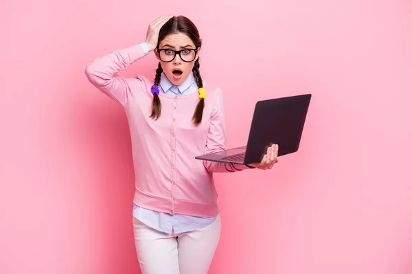 Retrato de ella que agradable atractivo bastante preocupado desconcertado de cabello castaño adolescente sosteniendo en la mano portátil utilizando el servicio de proyecto web aislado en el fondo de color pastel rosa — Foto de Stock