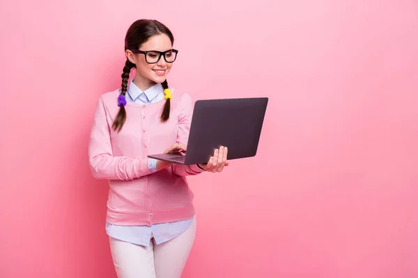 Profil photo de attrayant étudiant dame bonne humeur tenir ordinateur portable mains faire des devoirs en ligne vêtements chemise pull specs pantalon isolé couleur rose pastel fond — Photo