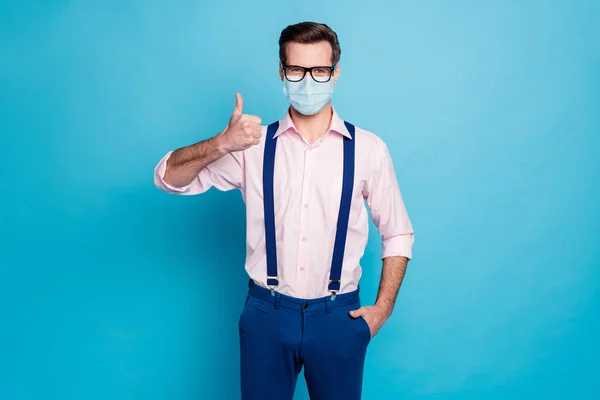 Retrato de su atractivo viajero chico sano con máscara de gasa mostrando pulgar inmunidad cuidado ayuda asistencia seguro de vida detener la gripe aislado brillante color azul vivo fondo — Foto de Stock